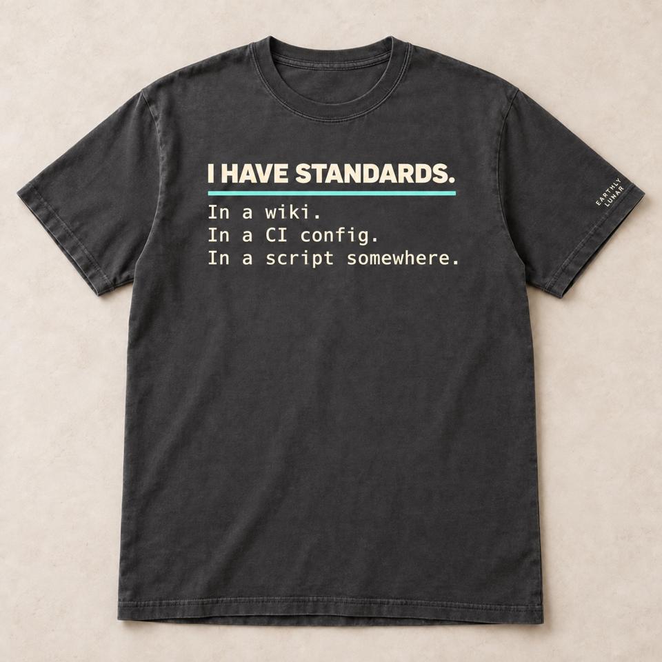 Charcoal tee with 'I HAVE STANDARDS.' underlined in mint over 'In a wiki. In a CI config. In a script somewhere.' in cream typewriter type