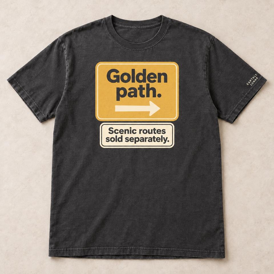 Charcoal tee with an amber road sign reading 'Golden path.' with a right arrow, over a cream plate reading 'Scenic routes sold separately.'