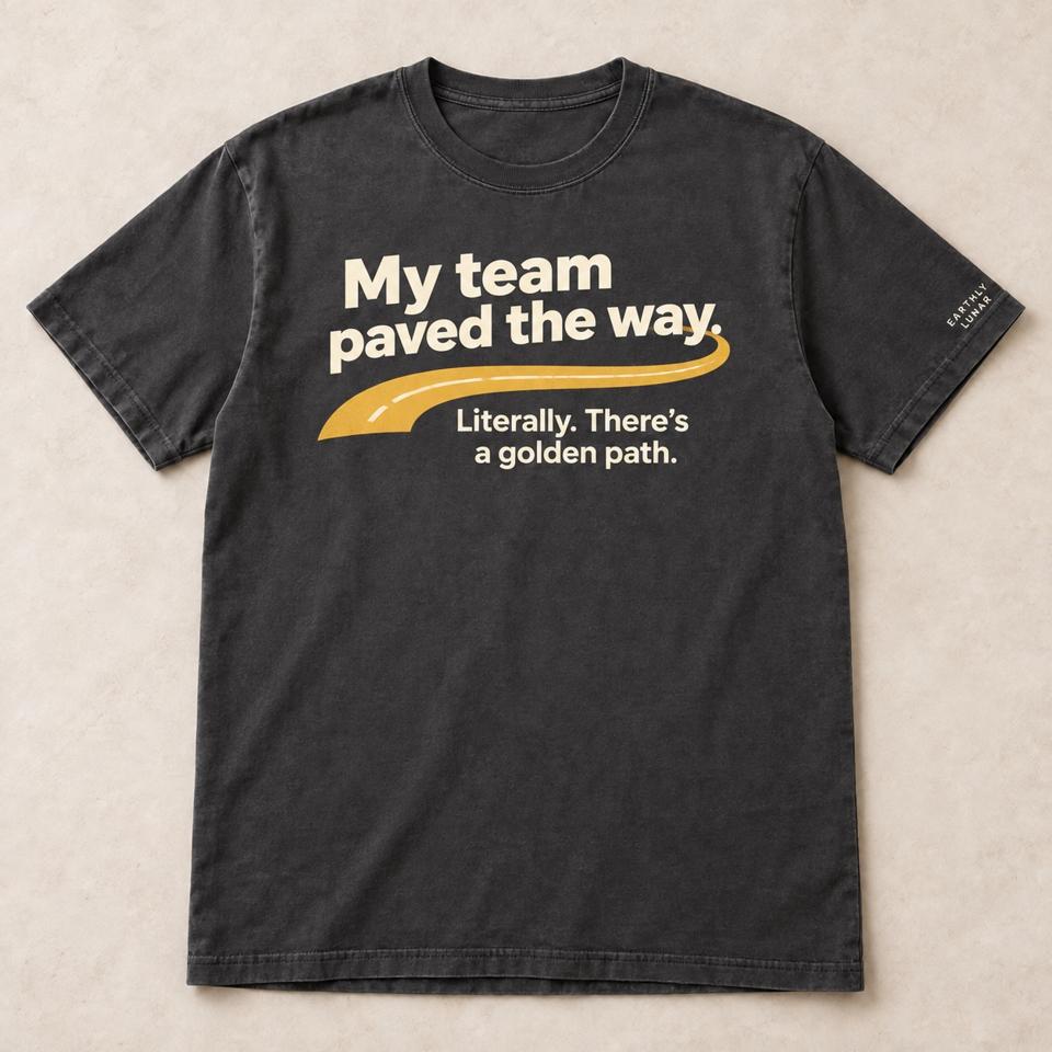 Charcoal tee with 'My team paved the way.' in cream over an amber road and 'Literally. There's a golden path.'