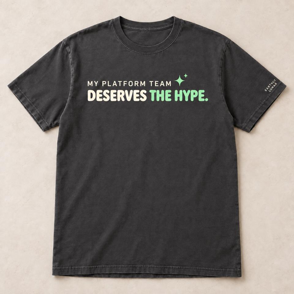 Charcoal tee with 'MY PLATFORM TEAM DESERVES THE HYPE.' in cream capitals, 'THE HYPE.' in mint beside a small sparkle
