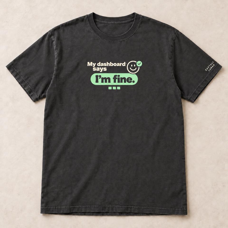 Charcoal tee with 'My dashboard says' in cream beside a smiling face and mint check, over 'I'm fine.' inside a mint pill